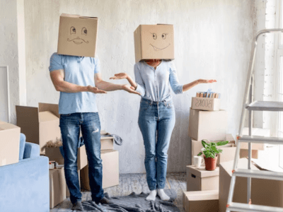 una coppia con scatoloni attorno e due scatole sul viso con degli smile