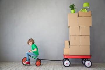bambino traina scatoloni con un triciclo